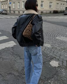 woman wearing leather jacket jeans and leopard purse