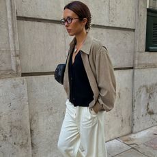 woman in beige jacket, cardigan, and white pants