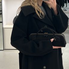 Eliza Huber carrying the new black suede Alaïa Le Teckel clutch in the brand's Paris flagship store. 